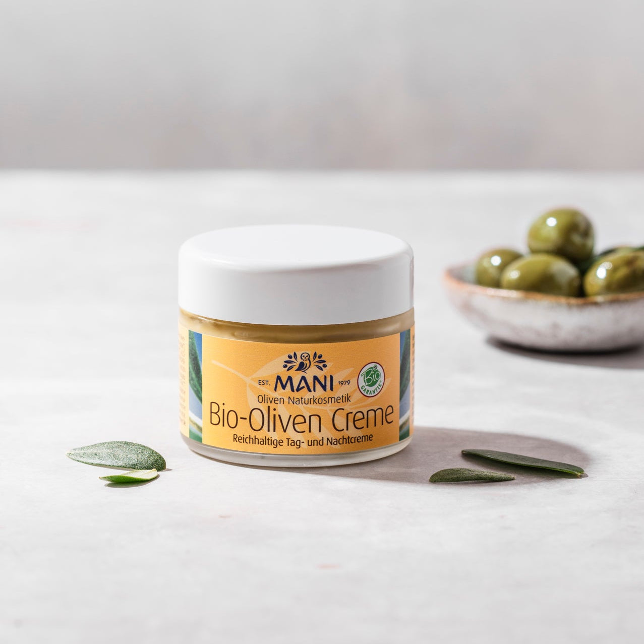 MANI Bio Oliven Creme, Olivenblätter und Schälchen mit Oliven