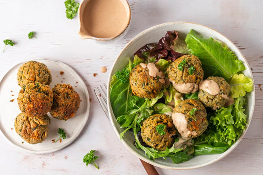 Falafel mit Tahinisauce auf Salat auf gedecktem Tisch