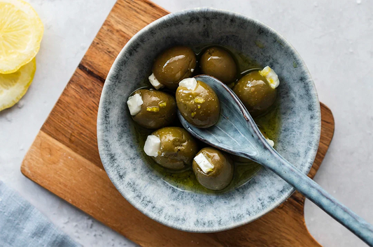 Mit Feta gefüllte Oliven mit Zitronenzesten in einem Schälchen