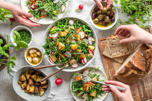 Gedeckter Tisch mit Frühlingssalat, Oliven, Knoblauch und Brot
