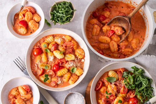 Gedeckter Tisch mit Gnocchi in cremiger Tomatensauce
