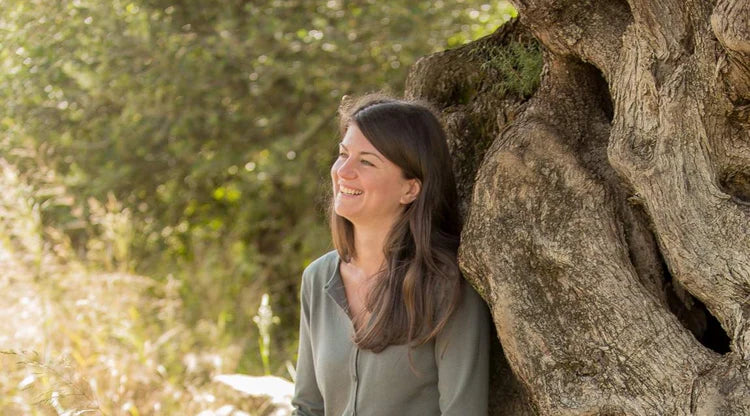 Julia Bläuel von MANI lehnt an Olivenbaum