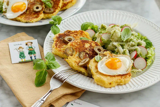 Kartoffelpancakes mit Spiegelei und Karfiolsalat und frischen Kräutern auf Teller