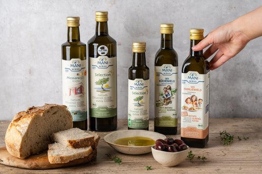MANI Bio-Olivenöle am gedeckten Tisch mit Brot und Olivenöl