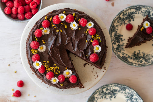Schokotorte mit Himbeeren Pistazien und Blumen dekoriert