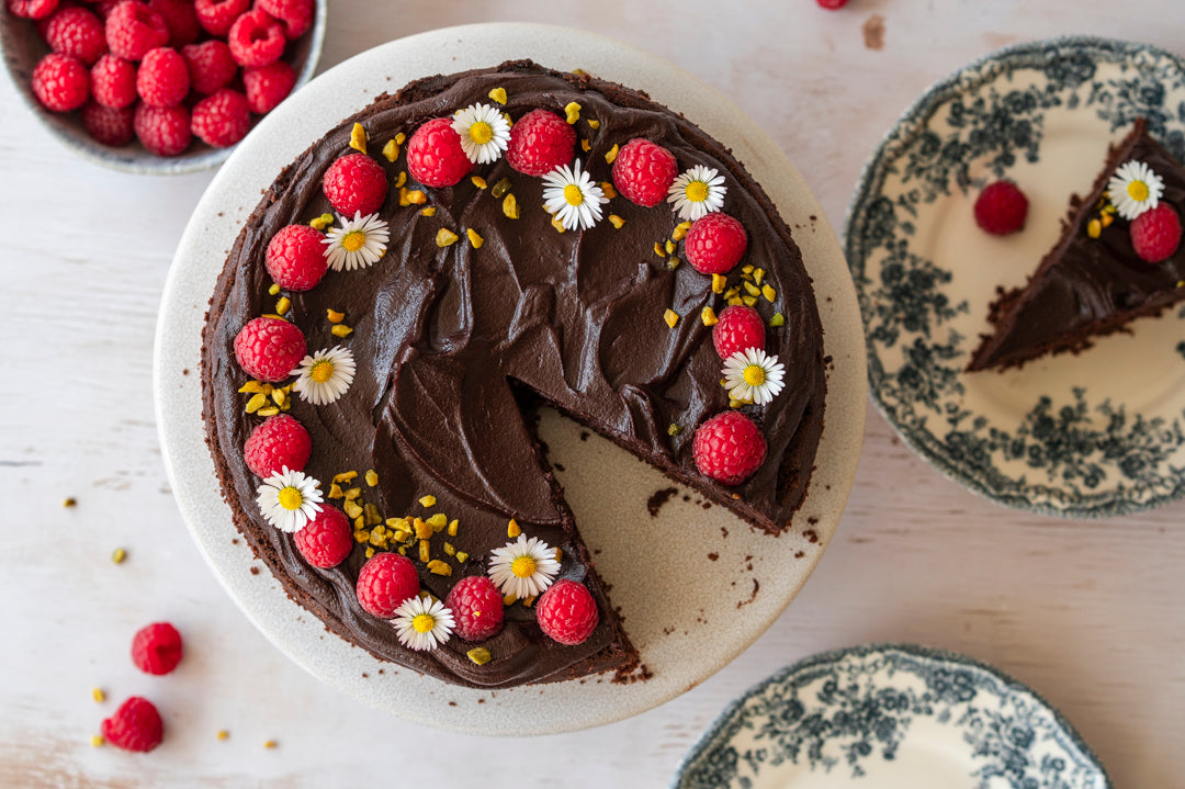Schokotorte mit Himbeeren Pistazien und Blumen dekoriert