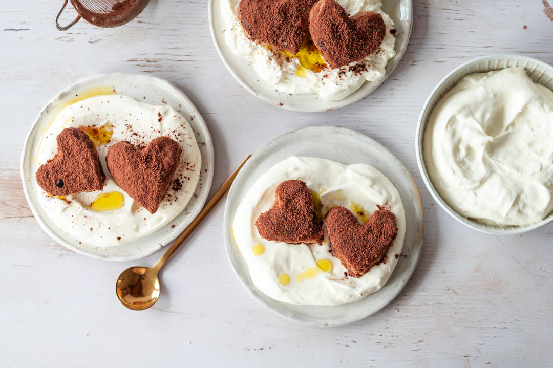 Tiramisu Herzen auf Creme mit Olivenöl auf gedecktem Tisch