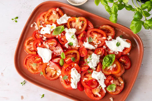 Tomatensalat mit Kräutern, Burrata und Olivenöl auf Servierplatte