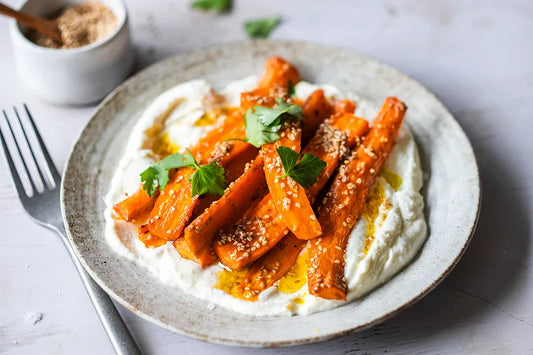 Karotten mit Whipped Feta, Sesam und Kräutern auf einem Teller