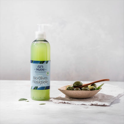 MANI Bio Oliven Flüssigseife neben Schälchen mit Oliven