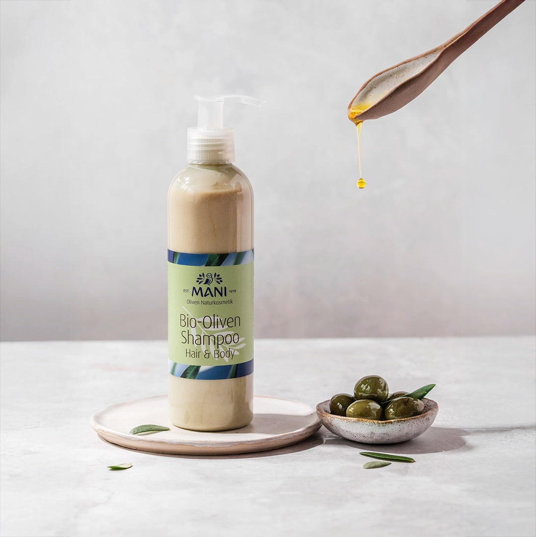 MANI Bio Oliven Shampoo Hair & Body neben Schälchen mit Oliven und Olivenöl