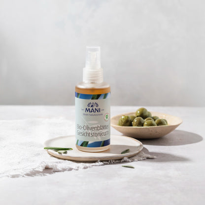 MANI Bio Olivenblätter Gesichtstonicum vor Schälchen mit Oliven