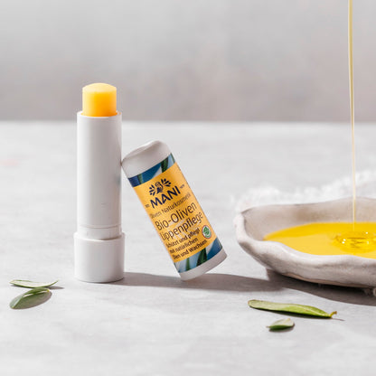 MANI Bio Oliven Lippenpflege neben Teller mit Olivenöl