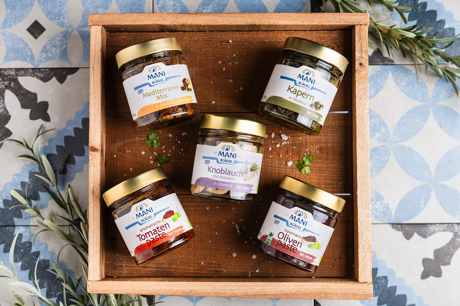 Mani Meze Produktsortiment auf Holzbrett mit Olivenzweigen